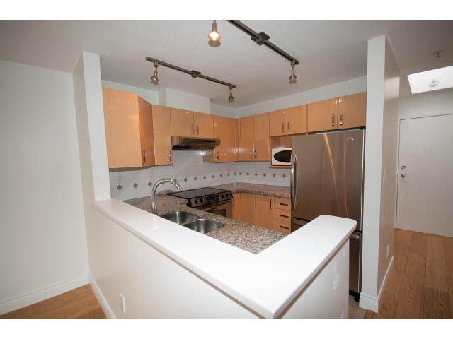 Bright kitchen with white cabinets, stainless steel appliances, and hardwood floors. - 409 - 3023 West 4th Ave., Vancouver West Side