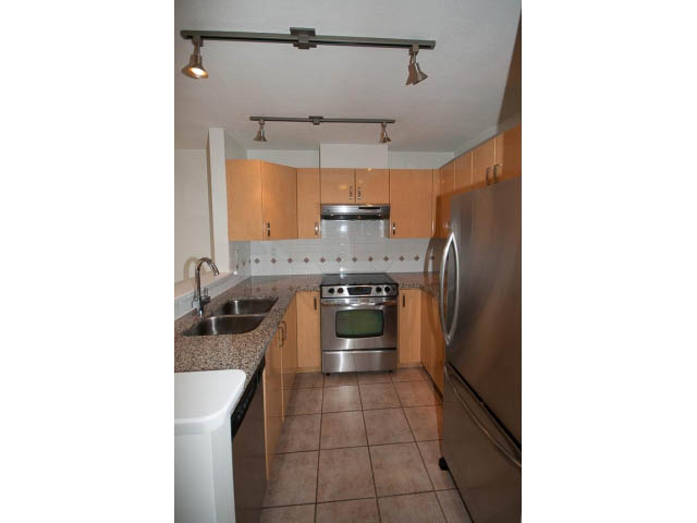 Bright kitchen with light wood cabinets, stainless steel appliances, and tiled floor. - 409 - 3023 West 4th Ave., Vancouver West Side