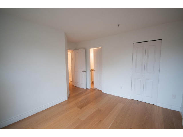 Bright living room with hardwood floors and white walls, leading to a den and another room. - 409 - 3023 West 4th Ave., Vancouver West Side