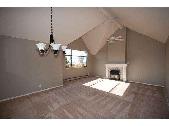 Spacious living room with vaulted ceiling, large windows, and carpeted floor. - 3 - 260 East 4th St, North Vancouver