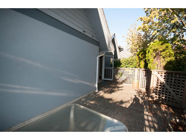 Fenced patio with gravel and lattice, leading to a house. - 3 - 260 East 4th St, North Vancouver