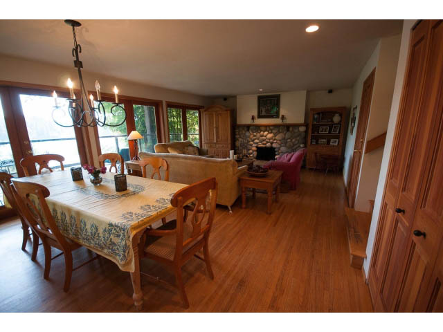 Furnished dining and living area with hardwood floors and a stone fireplace. - 2795 Panorama Drive, North Vancouver