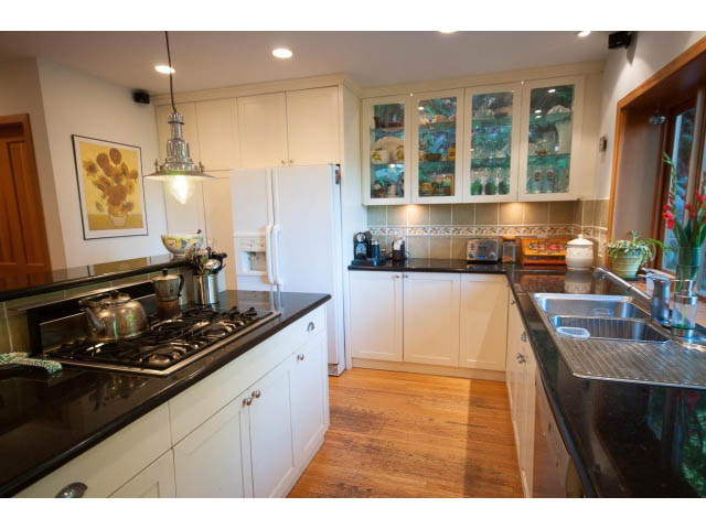 Bright kitchen with black countertops, hardwood floors, and a city view. - 2795 Panorama Drive, North Vancouver