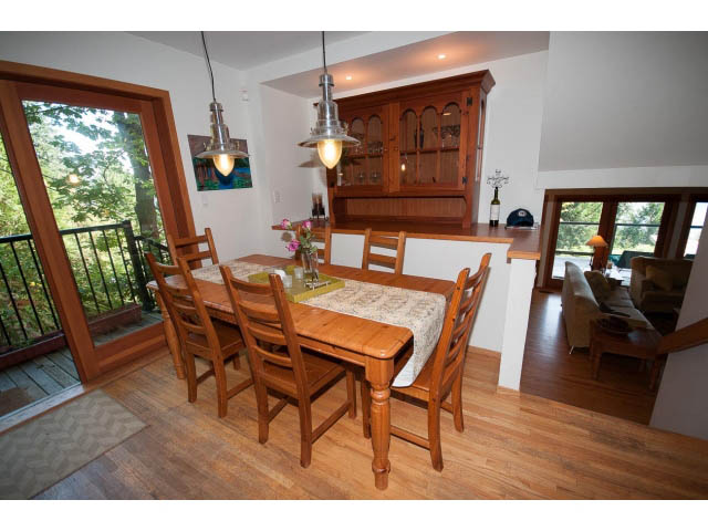 Bright dining area with wooden chairs, hardwood floors, and a view of greenery outside. - 2795 Panorama Drive, North Vancouver
