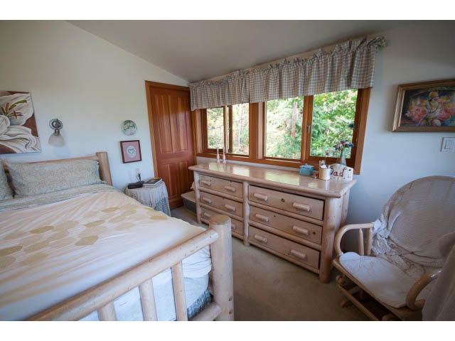 Bright bedroom with wooden furniture, large windows, and a view of greenery. - 2795 Panorama Drive, North Vancouver
