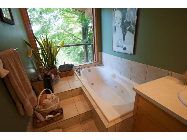 Bright bathroom with a large bathtub, green walls, and a window view. - 2795 Panorama Drive, North Vancouver