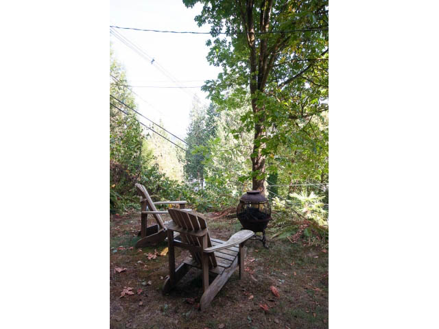 Furnished patio with wooden furniture and lush greenery. - 2795 Panorama Drive, North Vancouver