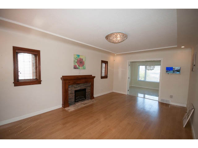 Bright living room with hardwood floors and a fireplace, featuring a chandelier and a floral artwork. - 3939 West 11th Ave, Vancouver West Side