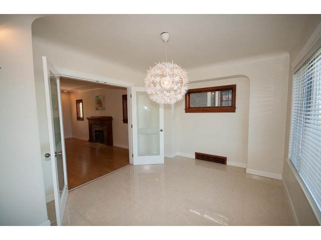 Bright living room with modern chandelier and large windows, leading to a cozy den with a fireplace. - 3939 West 11th Ave, Vancouver West Side