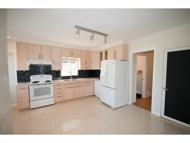 Bright kitchen with light wood cabinets, white appliances, and black tile backsplash. - 3939 West 11th Ave, Vancouver West Side