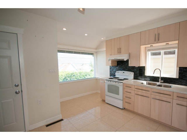 Bright kitchen with light wood cabinets, black backsplash, and white appliances. - 3939 West 11th Ave, Vancouver West Side