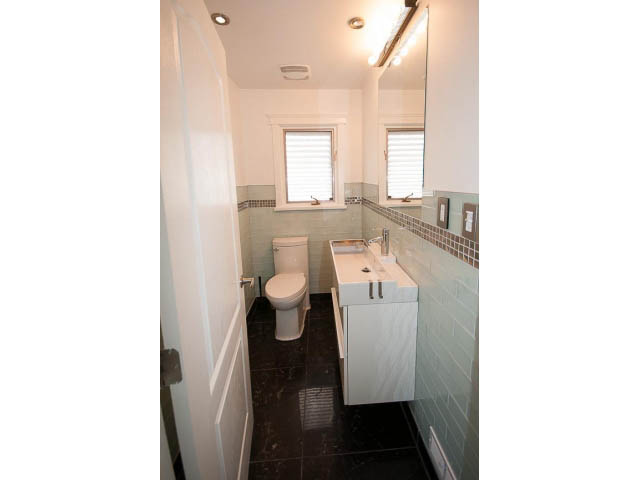 Furnished bathroom with white cabinetry, black tile flooring, and a window with blinds. - 3939 West 11th Ave, Vancouver West Side