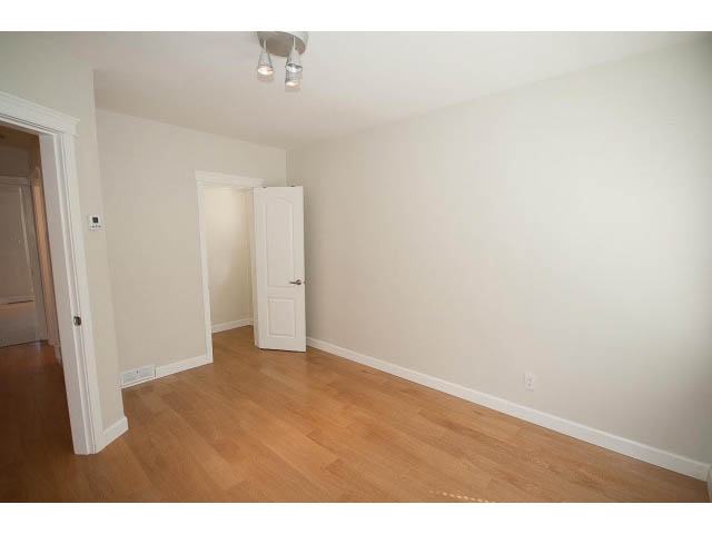 Spacious living room with hardwood floors and white walls, leading to a den. - 3939 West 11th Ave, Vancouver West Side
