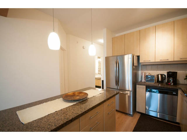 Bright kitchen with granite countertops, stainless steel appliances, and hardwood floors. - 411 - 560 Ravenwoods Dr., North Vancouver