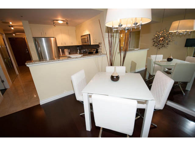 Furnished dining area with white chairs and modern light fixture. - 502 - 555 Jervis, Vancouver Downtown