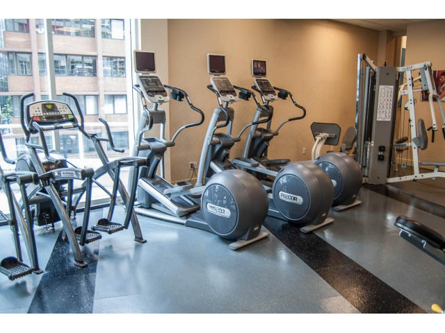 Bright fitness room with cardio machines and city view windows. - 3405-1111 W Pender, Vancouver Downtown