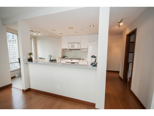 Bright kitchen with white cabinets and hardwood floors, featuring a city view through the window. - 1702 - 928 Beatty Street, Vancouver Downtown