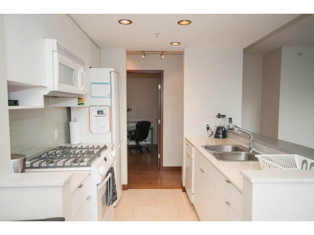 Bright kitchen with white cabinetry, stainless steel appliances, and hardwood floors. - 1702 - 928 Beatty Street, Vancouver Downtown