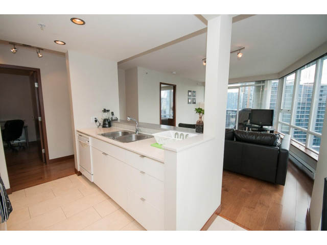 Bright kitchen with white countertops and hardwood floors, city view from the living area. - 1702 - 928 Beatty Street, Vancouver Downtown