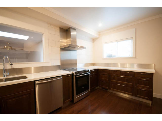 Bright kitchen with stainless steel appliances, hardwood floors, and a large window. - Main - 4149 Osler St, Vancouver West Side