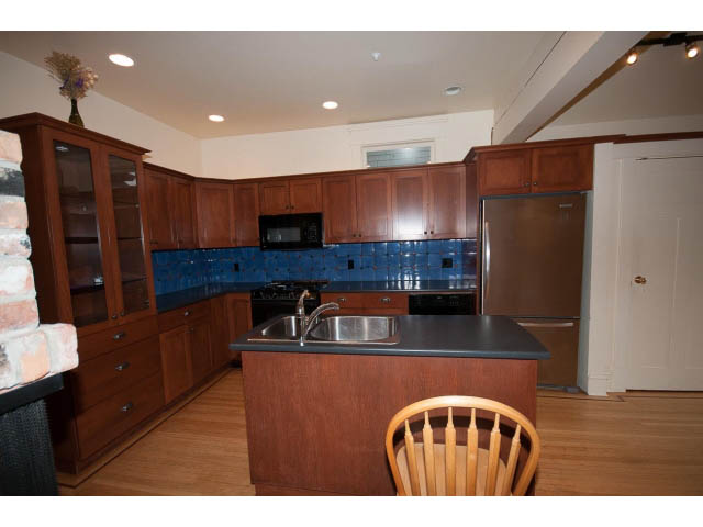 Bright kitchen with wooden cabinets, blue tile backsplash, and stainless steel appliances. - 3362 West 3rd Ave, Vancouver West Side