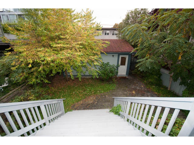 Staircase leading to a cozy, fenced backyard with trees and a small shed. - 3362 West 3rd Ave, Vancouver West Side
