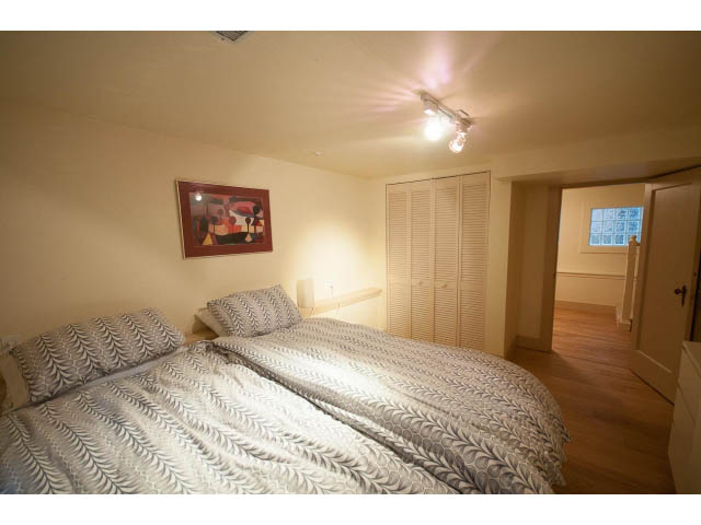 Furnished bedroom with hardwood floors and a patterned bedspread. - 3362 West 3rd Ave, Vancouver West Side