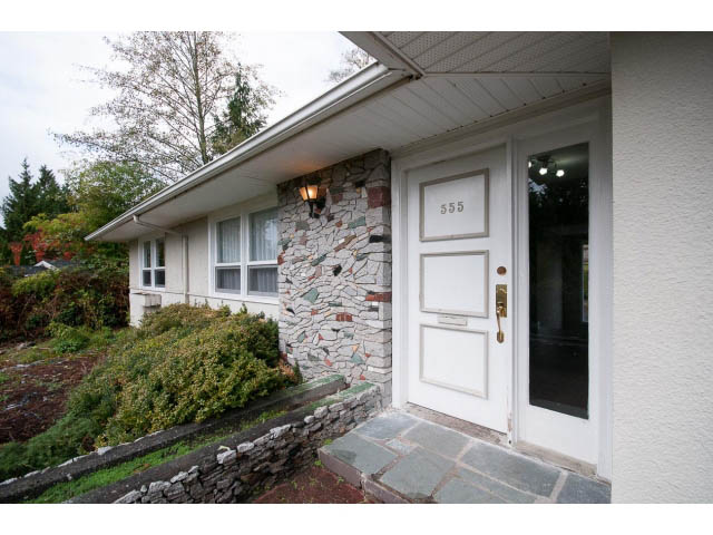 Furnished entryway with stone wall and glass door, leading to a cozy interior. - 555 Stevens Dr, West Vancouver