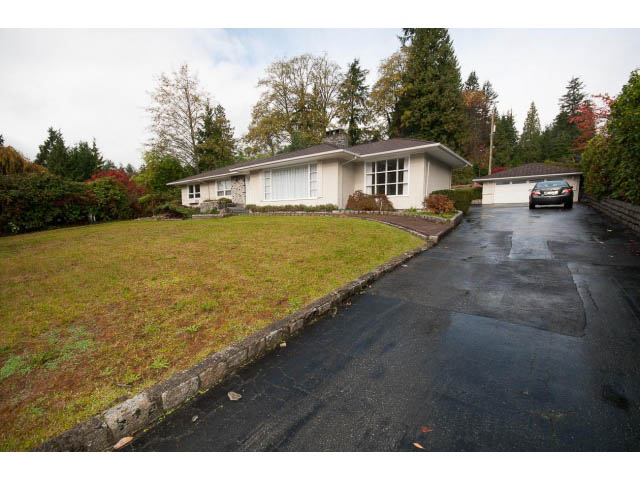 Furnished living room with large windows and greenery outside. - 555 Stevens Dr, West Vancouver