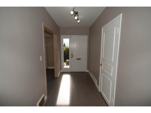 Bright hallway with hardwood floors and white trim, leading to a bright entryway. - 555 Stevens Dr, West Vancouver