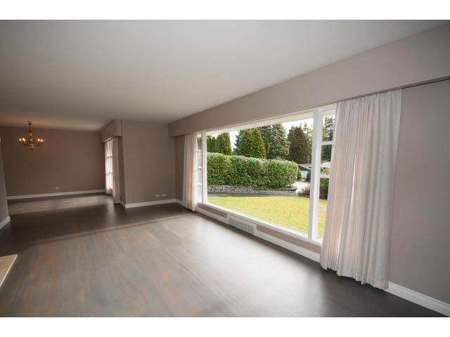 Spacious living room with hardwood floors and large windows overlooking greenery. - 555 Stevens Dr, West Vancouver