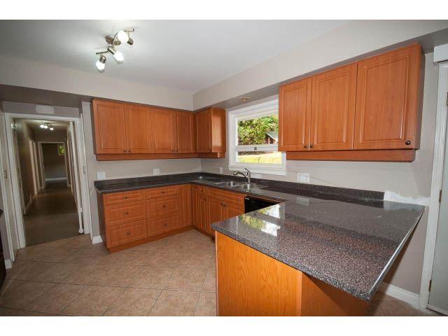 Bright kitchen with wooden cabinets, granite countertops, and tiled flooring. - 555 Stevens Dr, West Vancouver