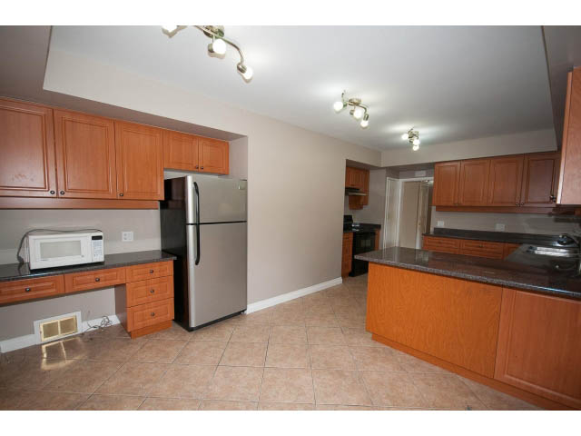 Bright kitchen with granite countertops and wooden cabinets, spacious layout. - 555 Stevens Dr, West Vancouver