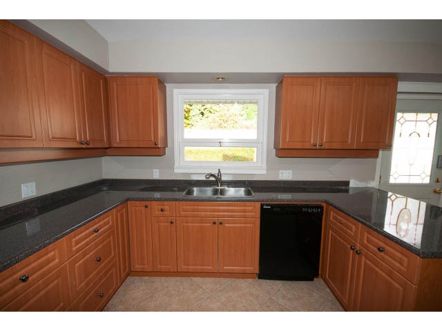 Bright kitchen with wooden cabinets, granite countertops, and a window view. - 555 Stevens Dr, West Vancouver