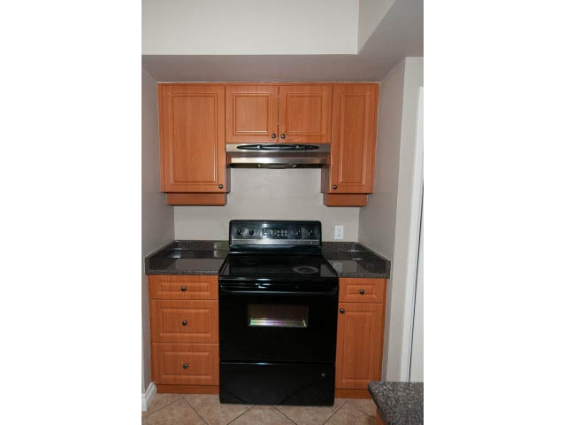 Bright kitchen with wooden cabinets, black appliances, and granite countertops. - 555 Stevens Dr, West Vancouver