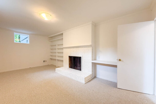 Spacious den featuring a white brick fireplace flanked by built-in shelving and a small desk nook. - 555 Stevens Drive, West Vancouver