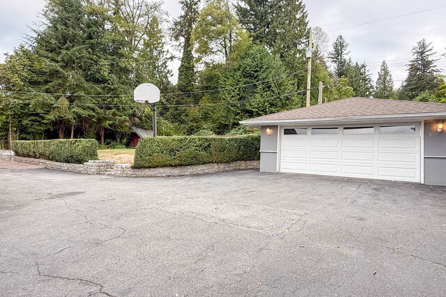 Spacious paved driveway with white double garage, manicured hedge, and basketball hoop. - 555 Stevens Drive, West Vancouver