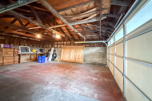 Spacious garage with exposed wooden ceiling beams and a stained concrete floor. - 555 Stevens Drive, West Vancouver