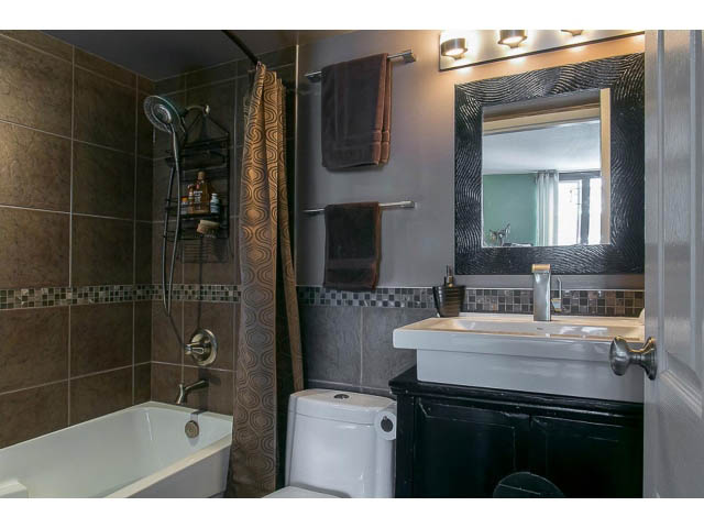 Furnished bathroom with dark vanity, tiled walls, and a bathtub. - 1505 - 488 Helmcken, Vancouver Downtown