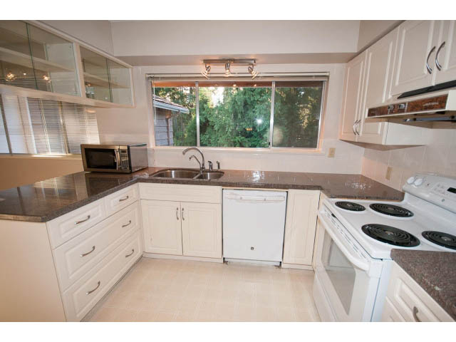Bright kitchen with granite countertops, white cabinets, and a large window view. - 610 Newdale Rd., West Vancouver