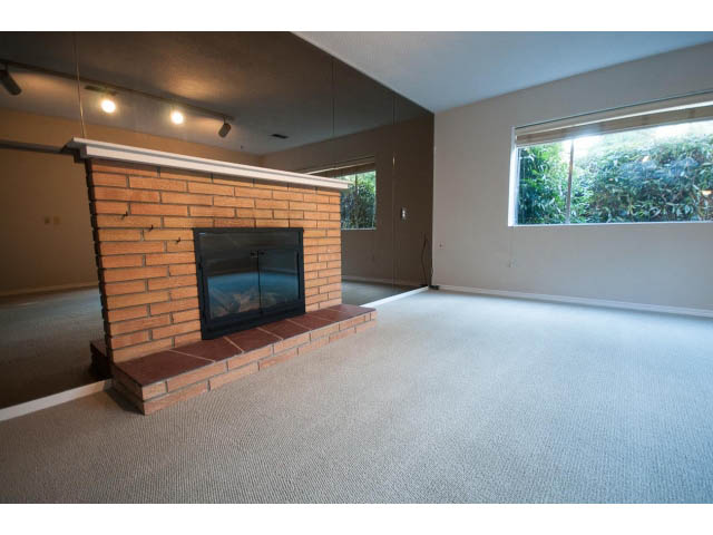 Bright living room with brick fireplace and large window view. - 610 Newdale Rd., West Vancouver