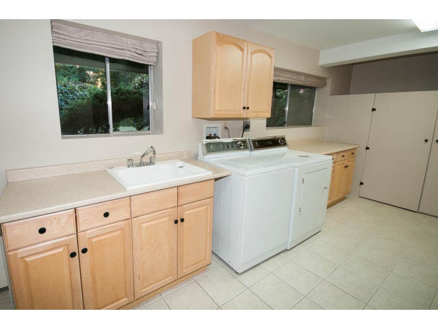 Bright laundry room with white appliances and beige countertops. - 610 Newdale Rd., West Vancouver
