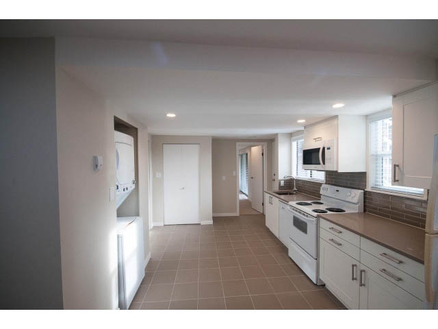 Bright kitchen with white cabinets, stainless steel appliances, and tiled floor. - Suite - 1719 Peters Rd, North Vancouver
