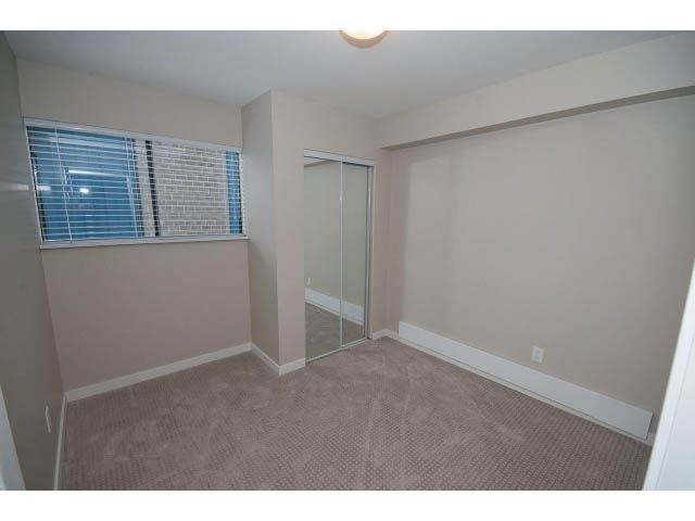 Spacious bedroom with carpeted floor and sliding glass door leading to balcony. - Suite - 1719 Peters Rd, North Vancouver
