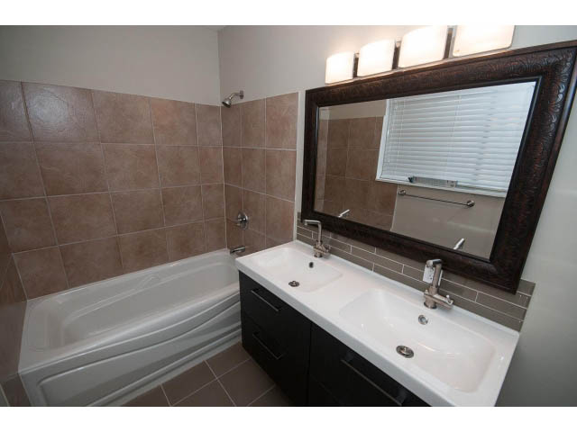 Furnished bathroom with white sink, dark vanity, and large mirror. - Suite - 1719 Peters Rd, North Vancouver