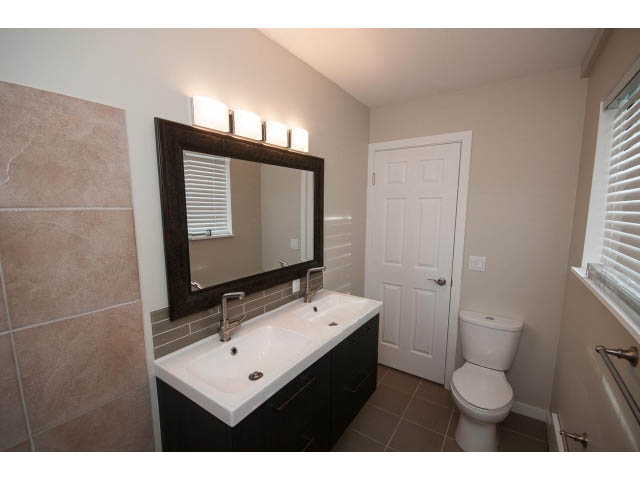 Bright bathroom with white fixtures and dark wood vanity, clean and modern. - Suite - 1719 Peters Rd, North Vancouver