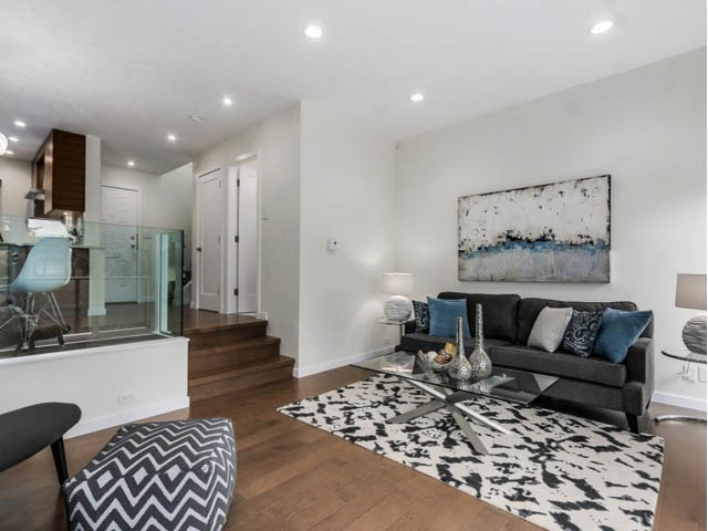 Spacious living room with hardwood floors, modern furniture, and a large abstract painting. - 1614 Maple St, Vancouver West Side