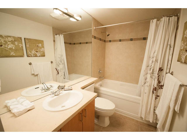 Furnished bathroom with beige tiles, white sink, and large mirror. - 708 - 193 Aquarius Mews, Vancouver Downtown