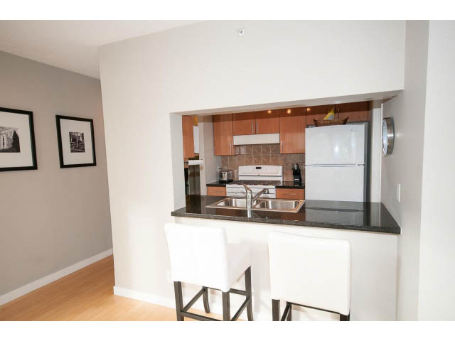 Bright kitchen with modern white cabinetry, granite countertops, and hardwood floors. - 708 - 193 Aquarius Mews, Vancouver Downtown
