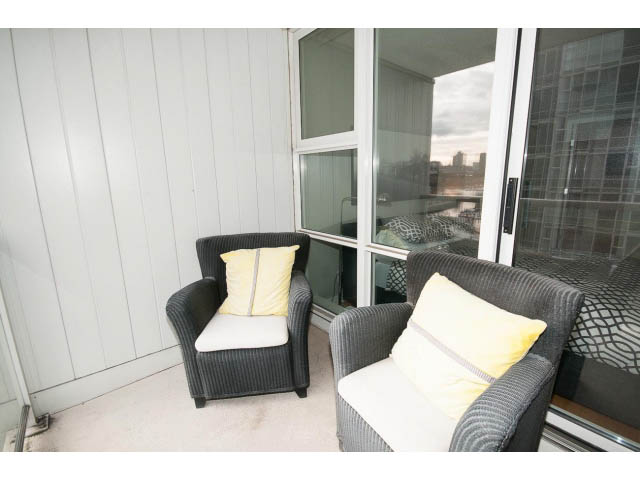 Furnished balcony with wicker furniture, city view, and large windows. - 708 - 193 Aquarius Mews, Vancouver Downtown